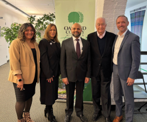 Five people stand together in front of a vibrant green banner.