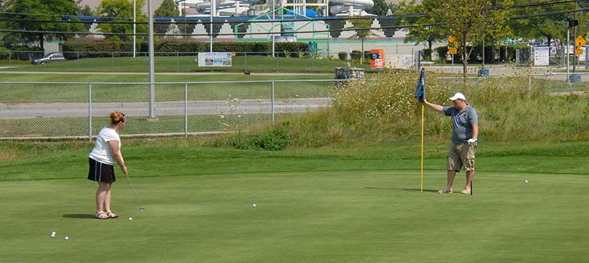 two golfers on a putting green at the Red Oaks Golf Course